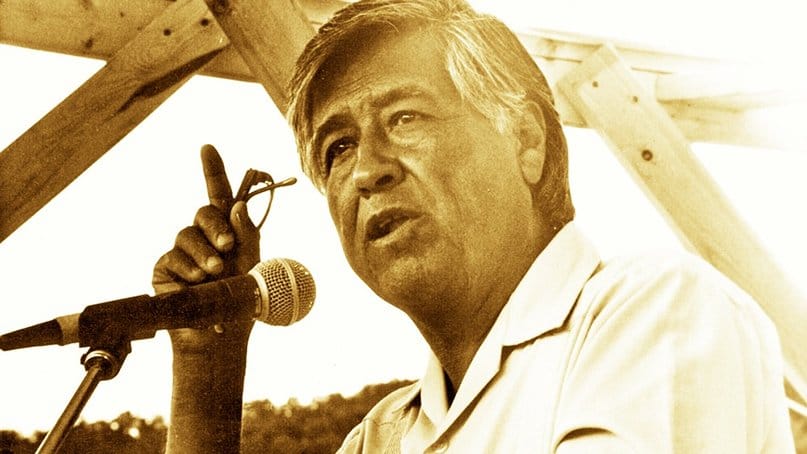 César Chávez speaking into a microphone and gesturing during a public address.