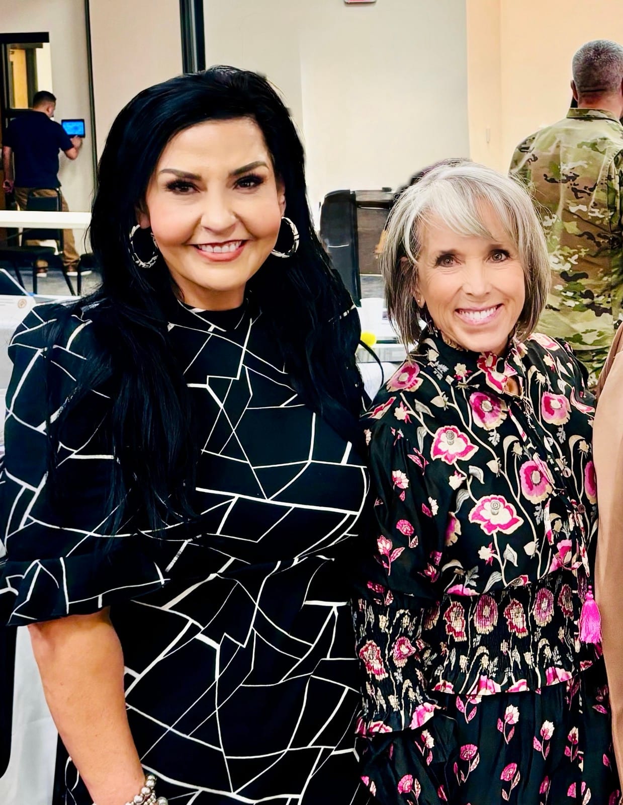 Amanda López Askin stands beside Gov. Michelle Lujan Grisham during a recent event. López Askin wears a black dress with white geometric lines.