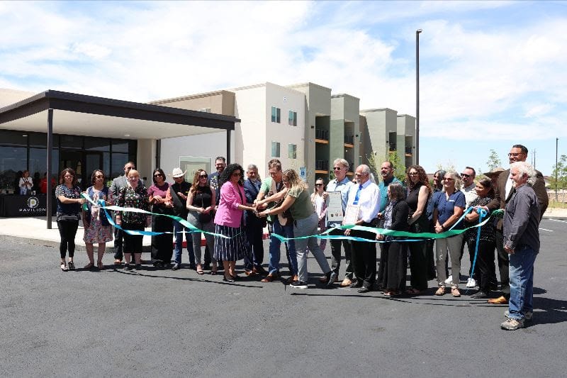 Officials and community members cut a ribbon in front of the newly opened Peachtree Canyon Apartments affordable housing development in Las Cruces.