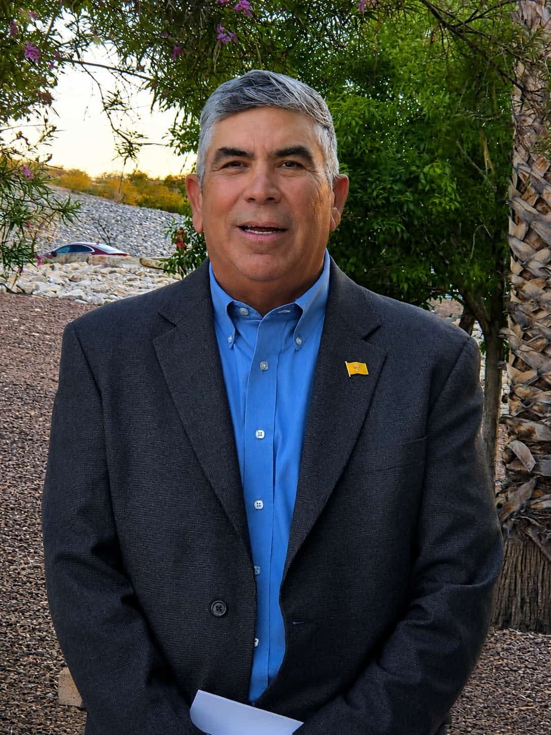 Democratic Doña Ana County sheriff candidate Eugene Alvarez poses outdoors wearing a blue shirt and dark blazer.