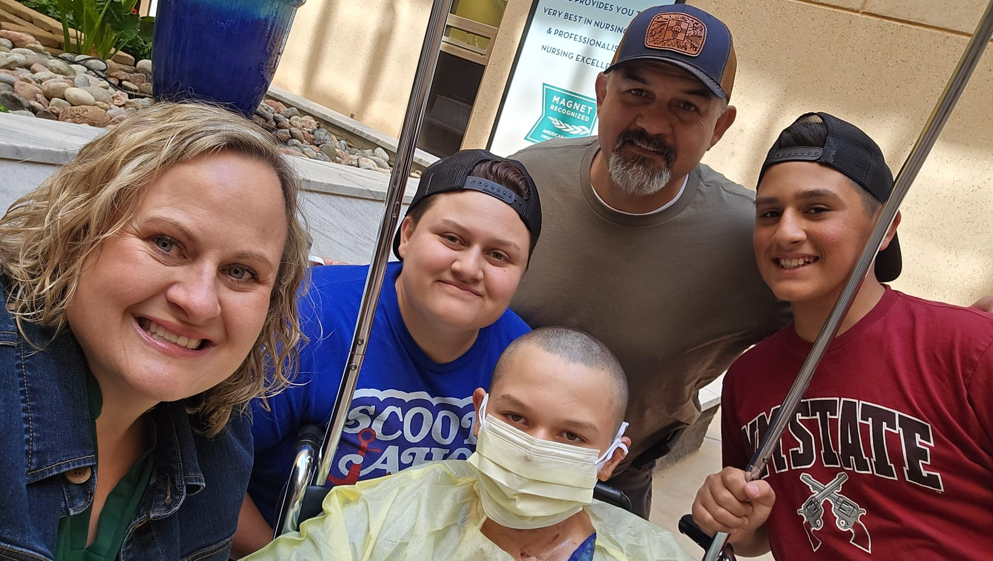 Matthew Garcia sits with family members in a hospital courtyard, wearing a face mask following burn treatment.