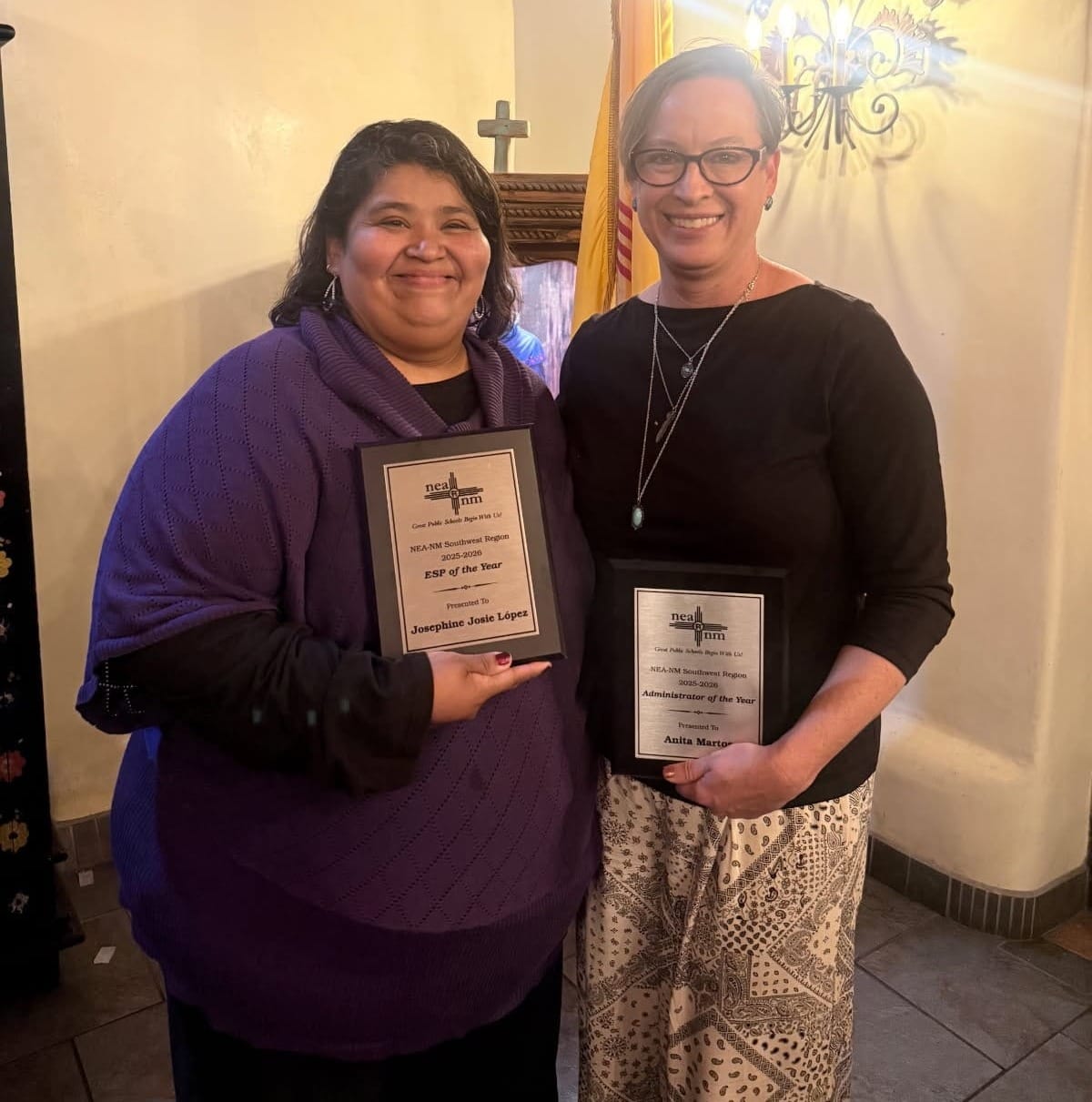 Josephine Lopez and Anita Martos stand together holding statewide education award plaques at an awards ceremony.
