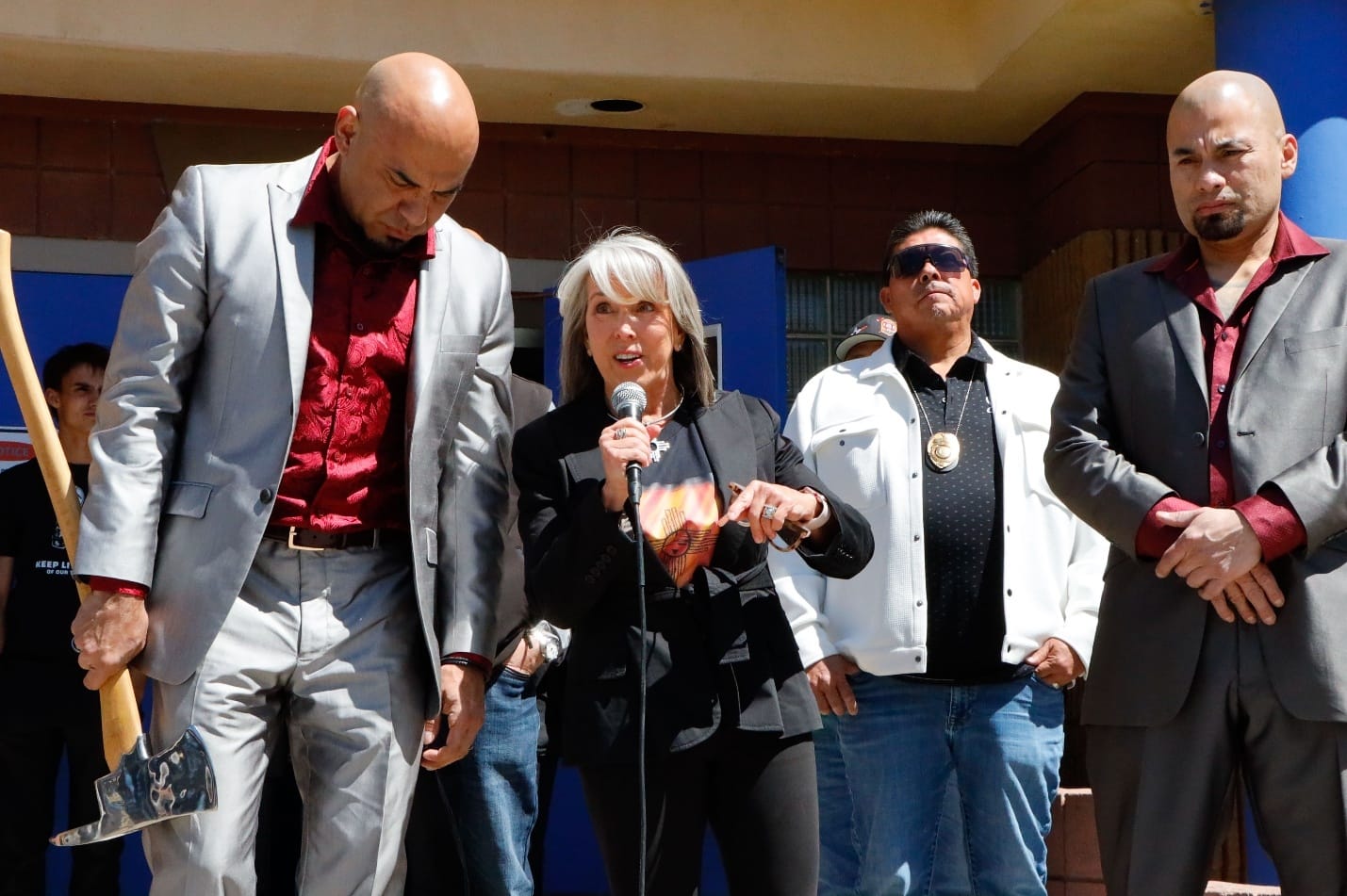 Gov. Michelle Lujan Grisham speaks at a cleanup event in Española while actors Luis and Daniel Moncada, known as the Salamanca Cousins from Breaking Bad, stand nearby.