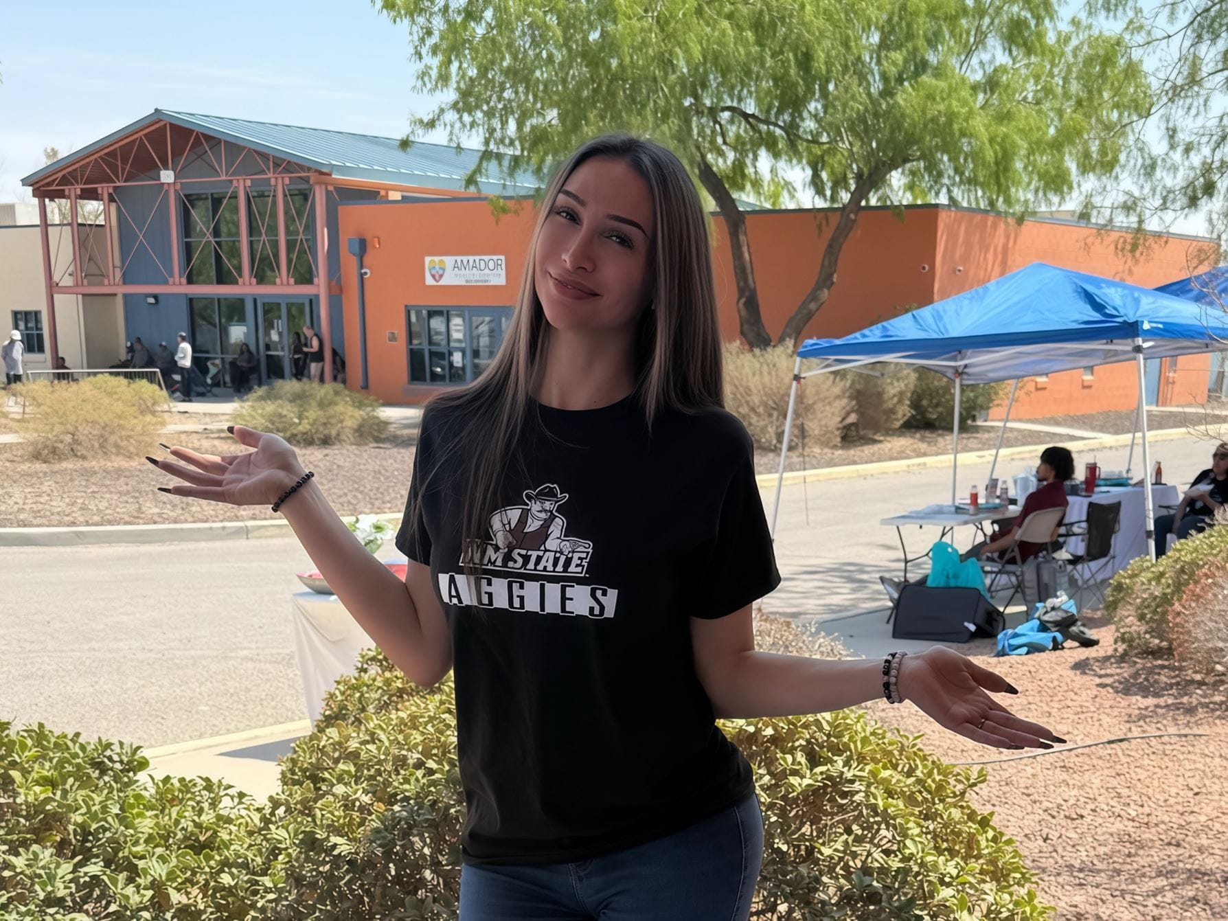 NMSU graduate Janessa Clark poses outdoors on campus while wearing an Aggies T-shirt.