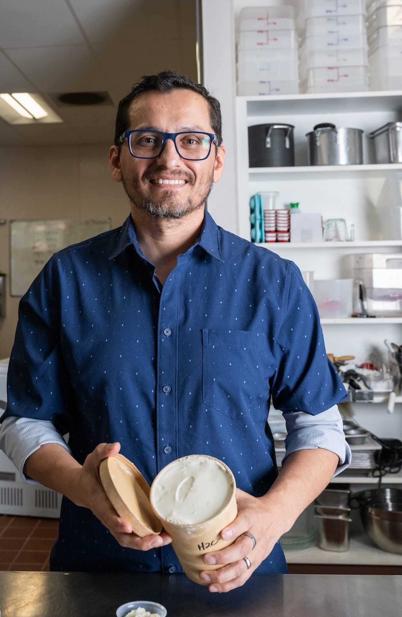 New Mexico State University assistant professor Sergio Martinez-Monteagudo holds an open container of ice cream while standing in the campus food science dairy lab.