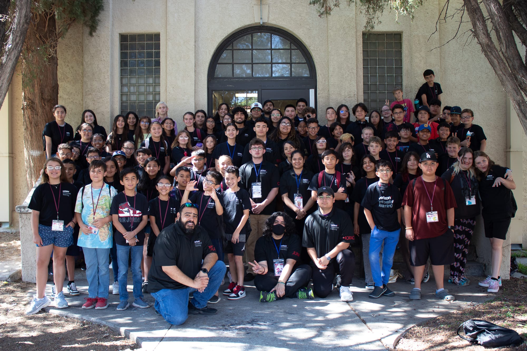 Dozens of middle school students and instructors pose for a group photo outside a campus building during New Mexico State University’s STEM Achievers summer camp.