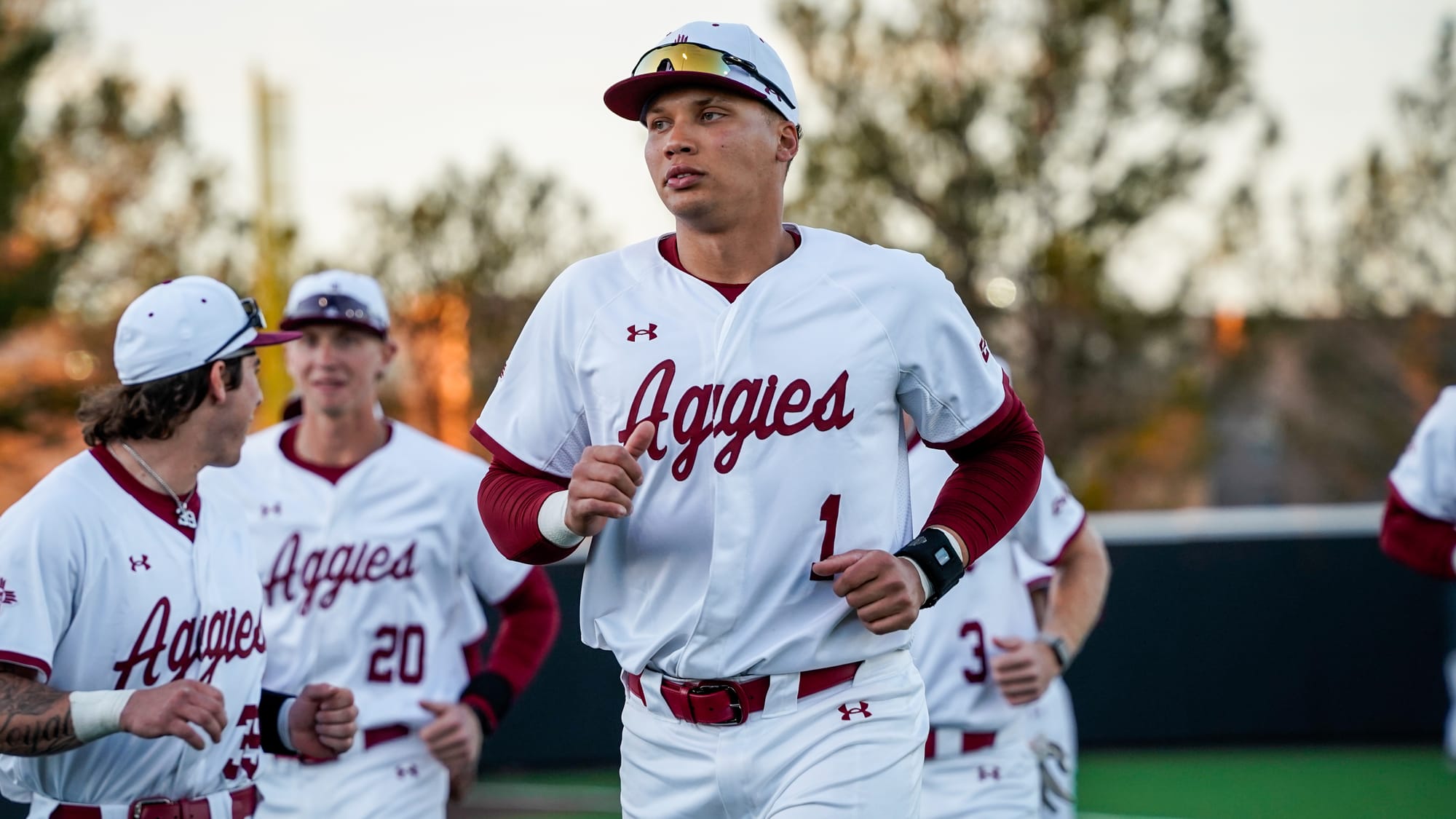 NM State baseball player Jonatan Clough jogs onto the field with teammates during a game.