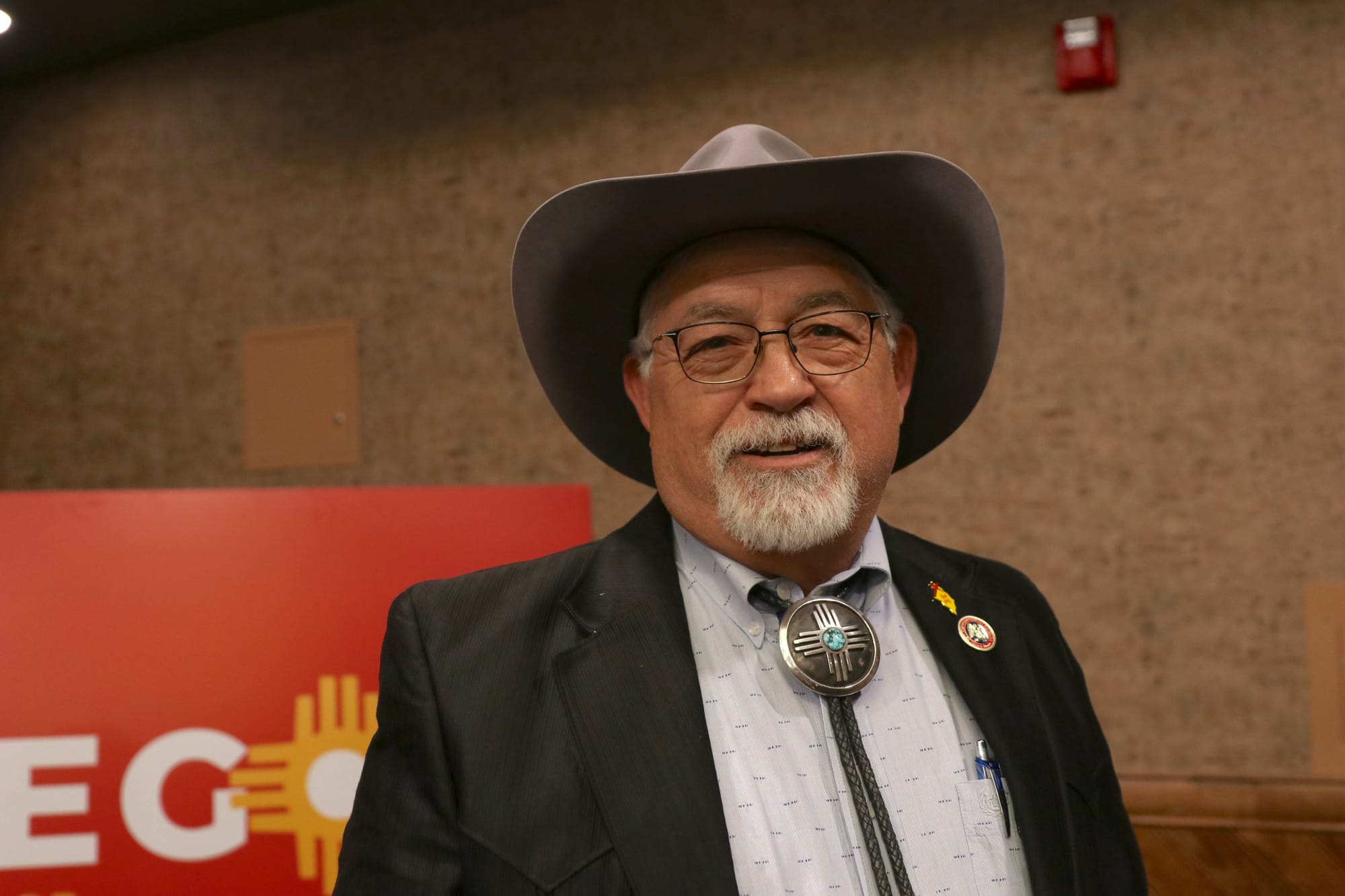 Portrait of New Mexico Sen. David Gallegos wearing a cowboy hat and bolo tie, standing indoors.