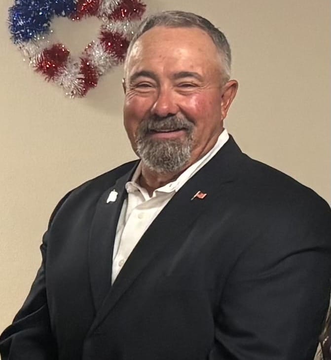 Republican Doña Ana County sheriff candidate Todd Garrison poses for a portrait wearing a dark suit jacket and white shirt.