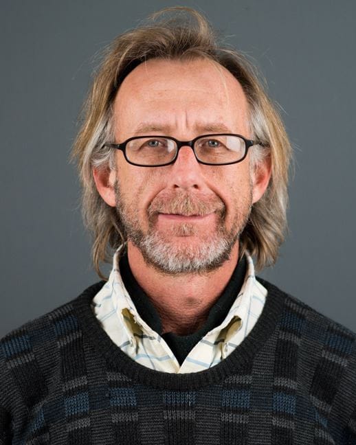 Western New Mexico University history professor Scott Fritz poses for a portrait wearing glasses and a patterned sweater.