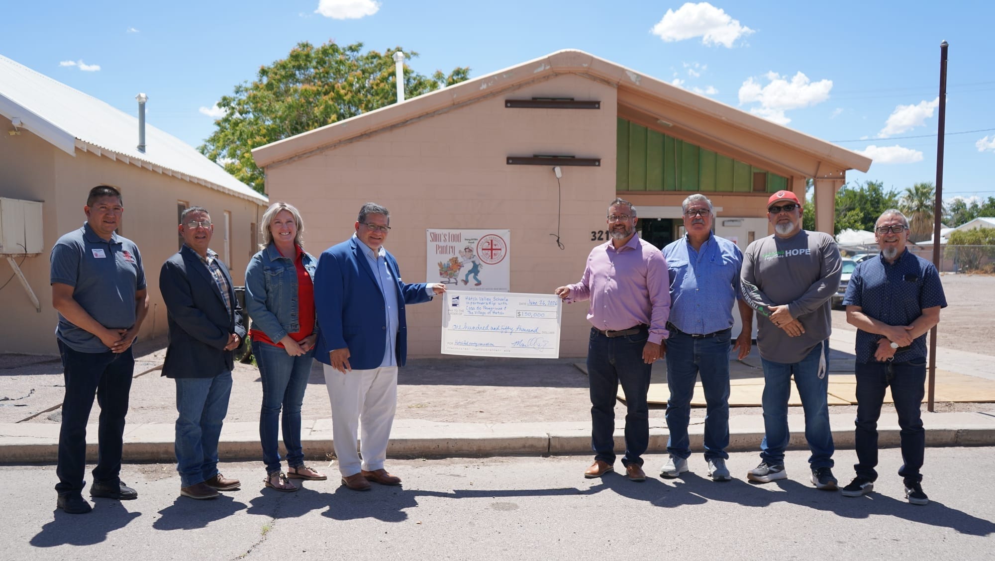 Lorenzo Alba, Manuel Sanchez and local stakeholders stand outside Slim’s Food Pantry in Hatch with a $150,000 check for pantry renovations.