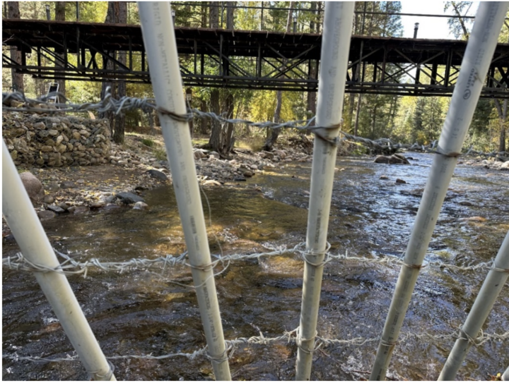 PVC pipes threaded with barbed wire form a fence across the Pecos River beneath a bridge near Erik Briones’ property.