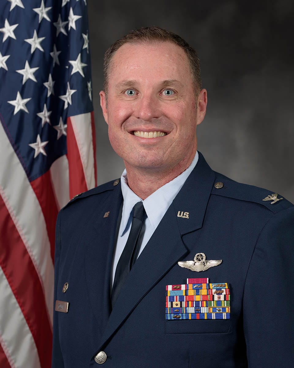 U.S. Air Force Col. Michael Mullin poses for an official portrait in uniform beside an American flag.
