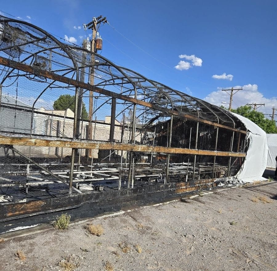 Fire-damaged greenhouse with blackened framing and burned covering on Nevada Avenue in Las Cruces.