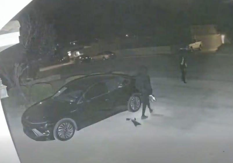 Surveillance image shows two auto burglary suspects near a parked vehicle at night in Las Cruces.
