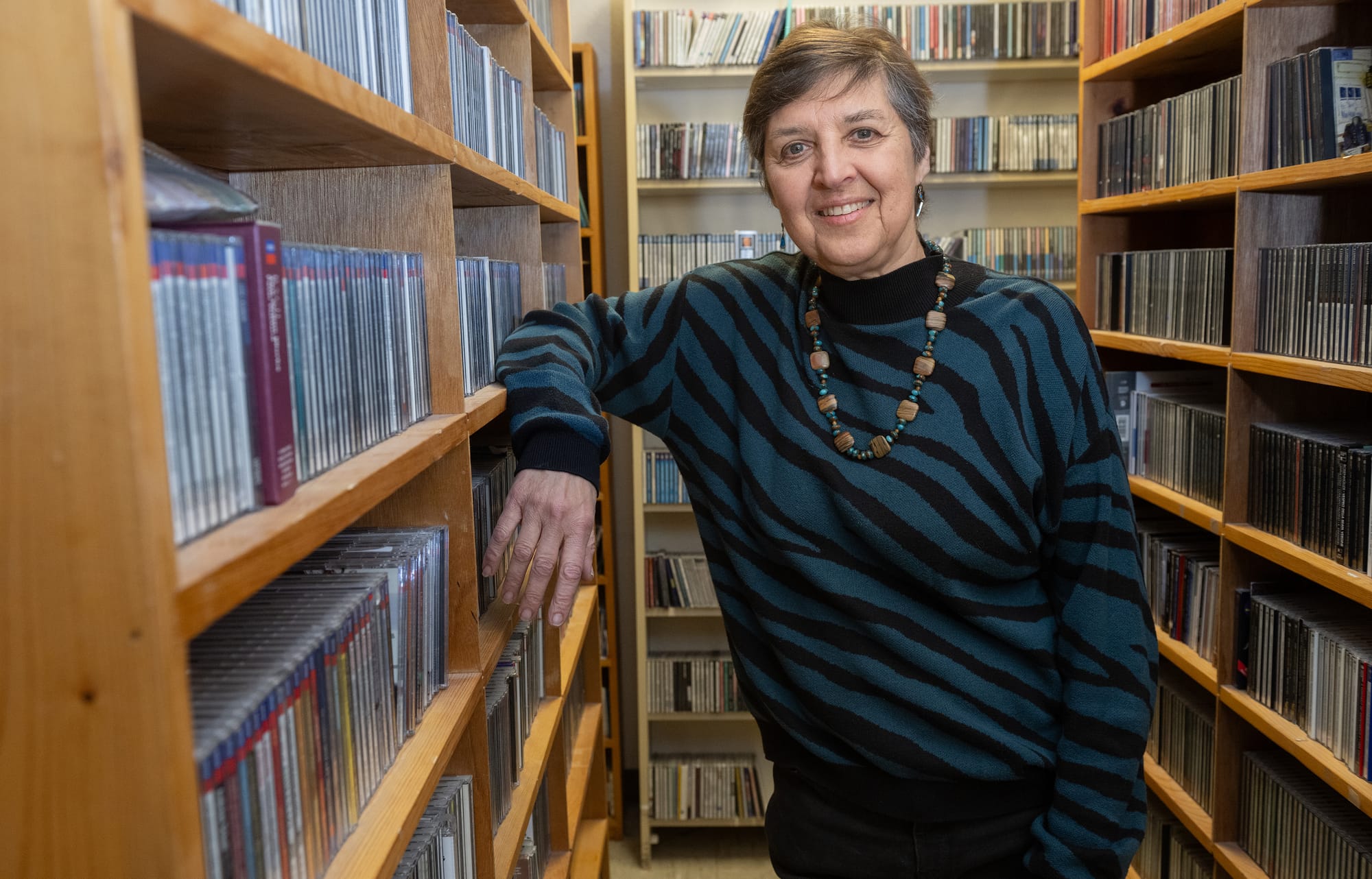 Leora Zeitlin stands between shelves of CDs at KRWG Public Media.
