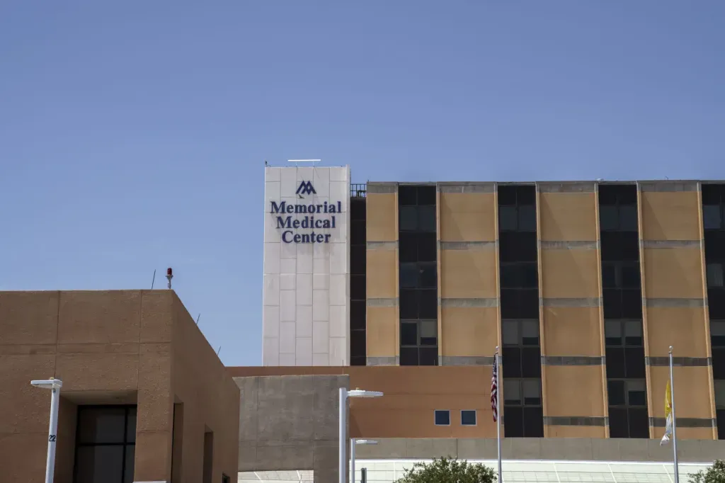 The exterior of Memorial Medical Center in Las Cruces, with the hospital’s name displayed on a tall section of the building beneath a clear blue sky.