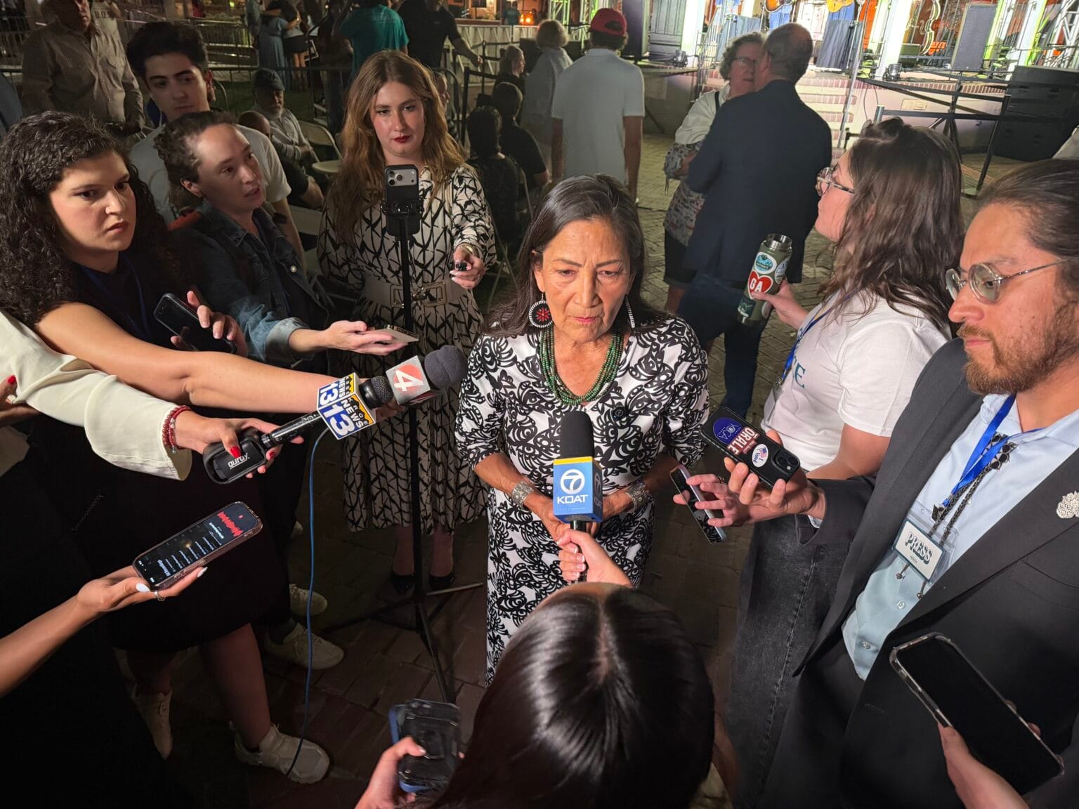 Deb Haaland speaks with reporters on election night as microphones, phones and cameras are held around her outside a campaign event.