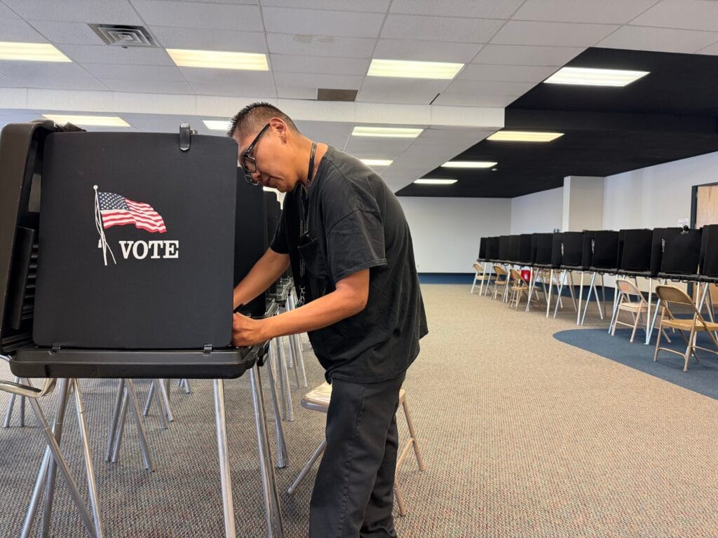Tyson Benally marks a ballot inside a privacy booth at an Albuquerque early voting center after marching there with Democratic gubernatorial candidate Deb Haaland.