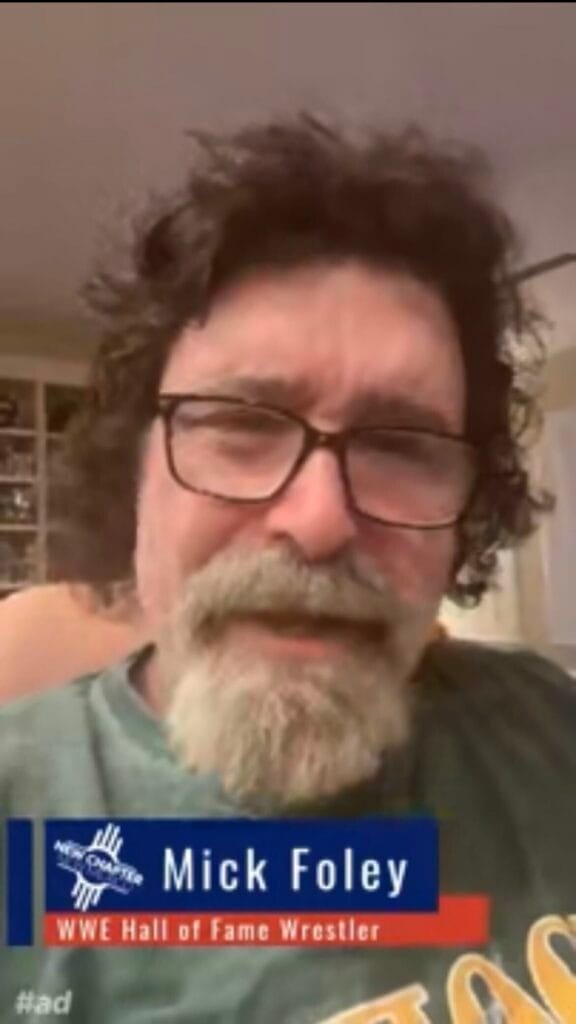 A screenshot from a political advertisement shows professional wrestling hall-of-famer Mick Foley speaking to the camera, with an on-screen graphic identifying him by name.
