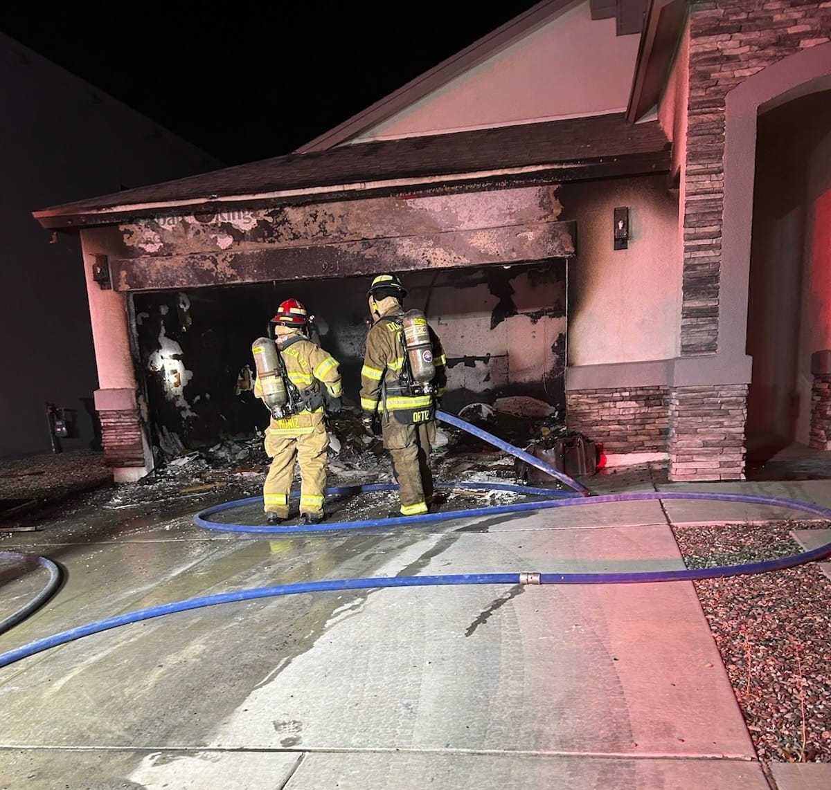 Firefighters stand outside a fire-damaged garage at a Sunland Park home early Wednesday morning.