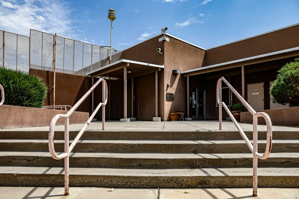 Entrance to the Youth Diagnostic and Development Center in Albuquerque, with stairs, railings and fencing visible outside the building.
