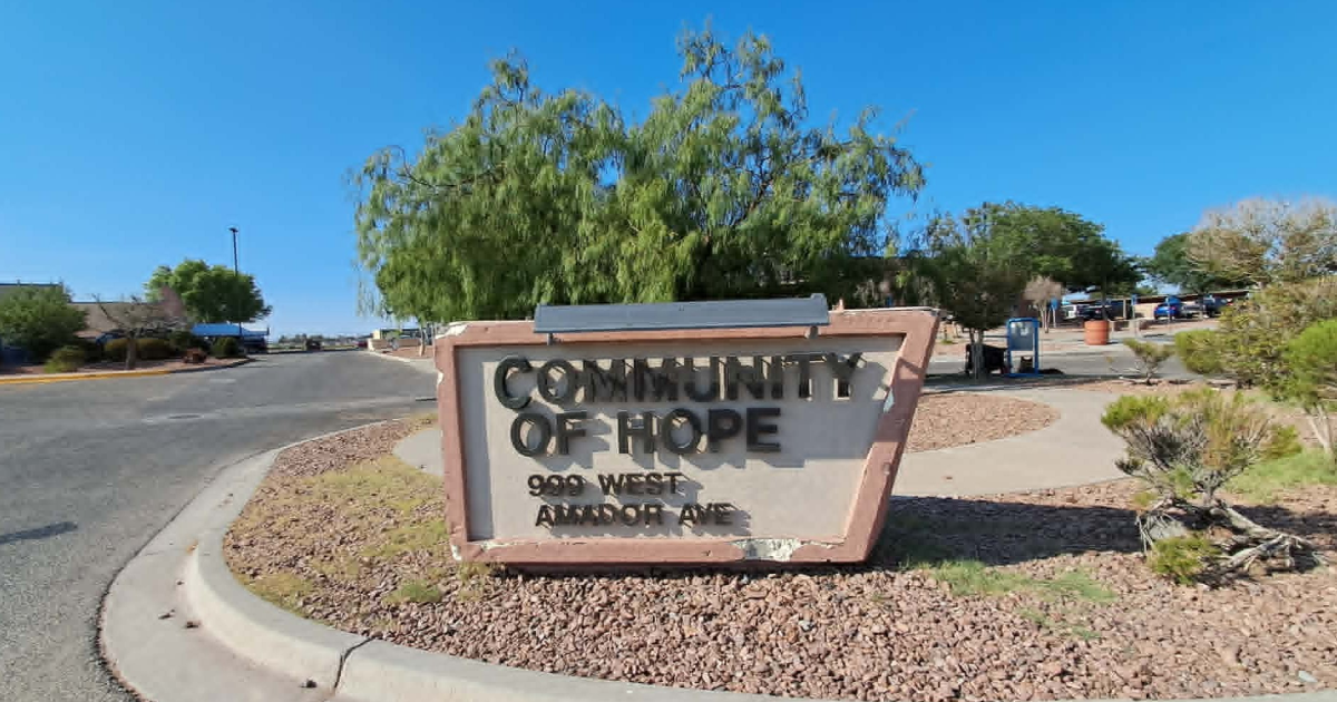 Entrance sign for Mesilla Valley Community of Hope at 999 W. Amador Ave. in Las Cruces, with campus buildings visible behind it.