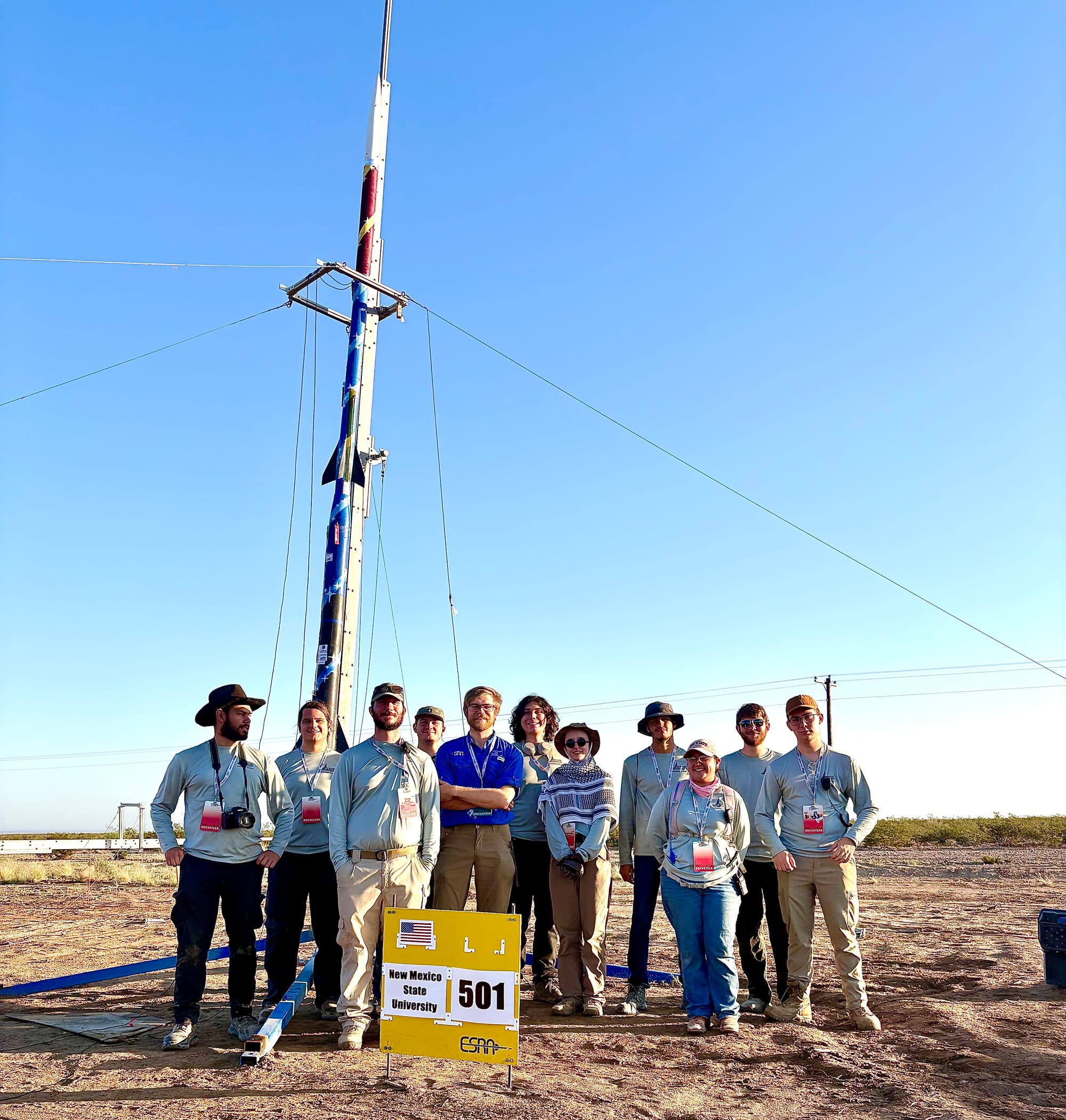 The team stands with their safety check lead in front of the rocket they built.
