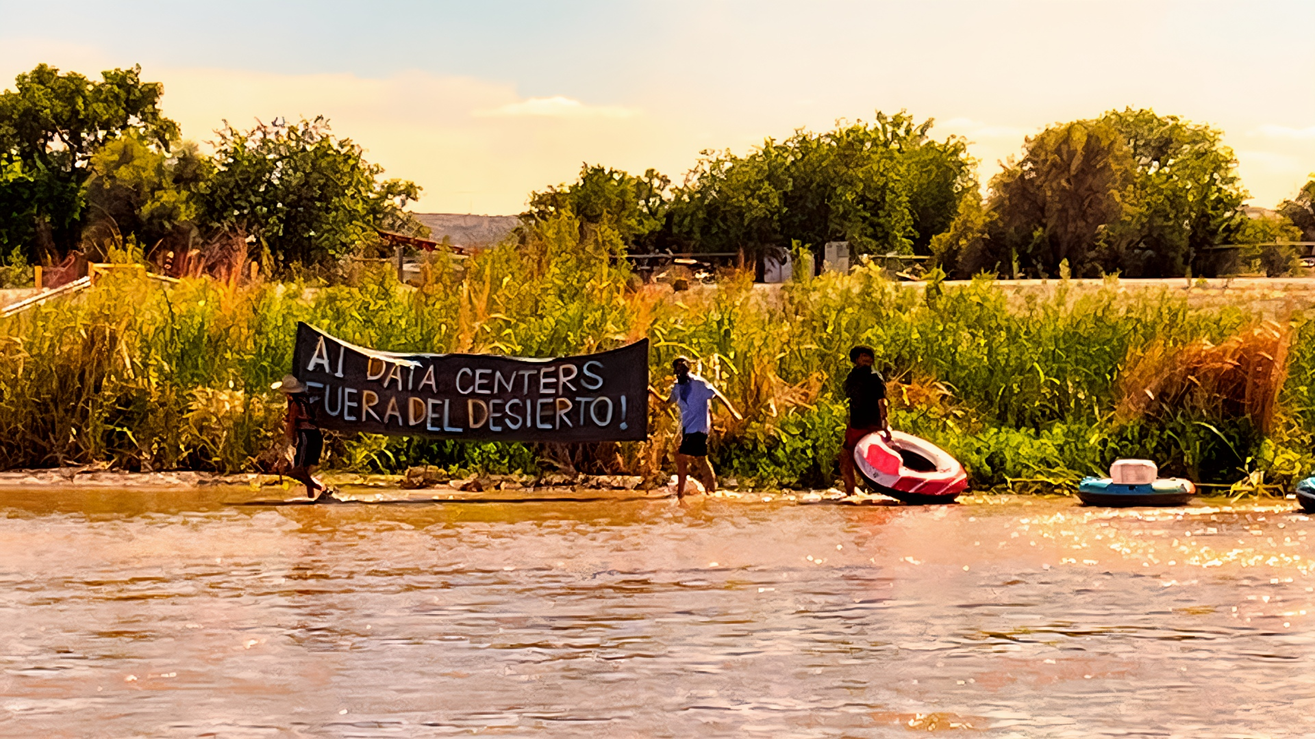 Protesters hold a black banner along the Rio Grande that reads, “AI data centers fuera del desierto!”