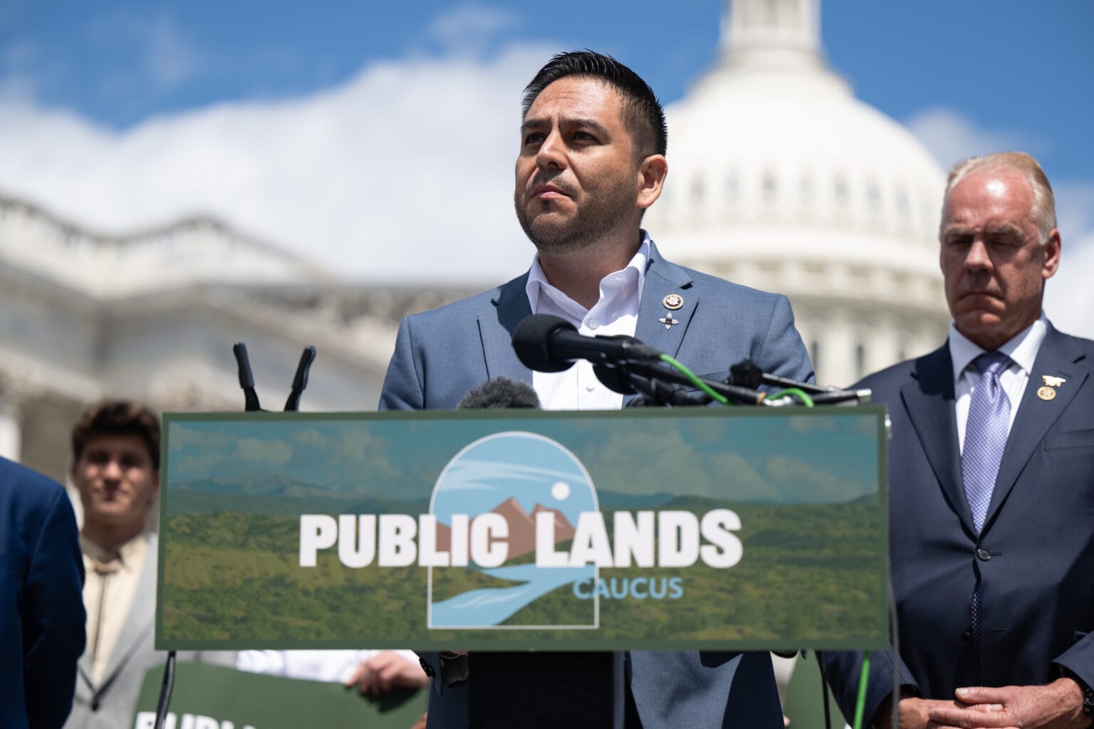U.S. Rep. Gabe Vasquez speaks at a Public Lands Caucus event outside the U.S. Capitol as U.S. Rep. Ryan Zinke stands behind him.