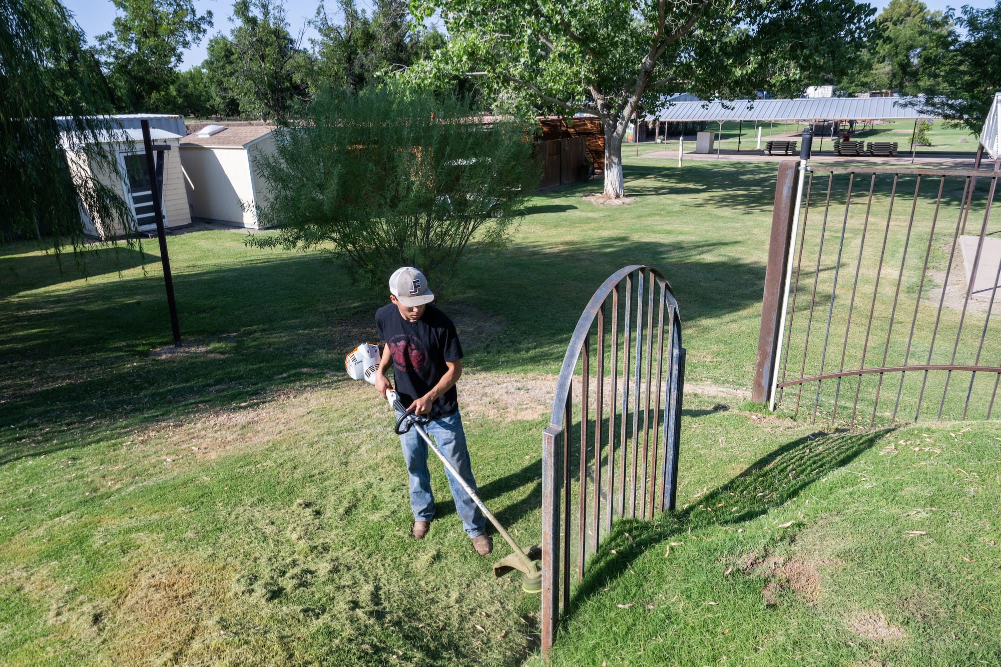 NMSU freshman Santiago Gamboa uses a string trimmer near a metal gate during his internship at Mesilla Valley Maze.