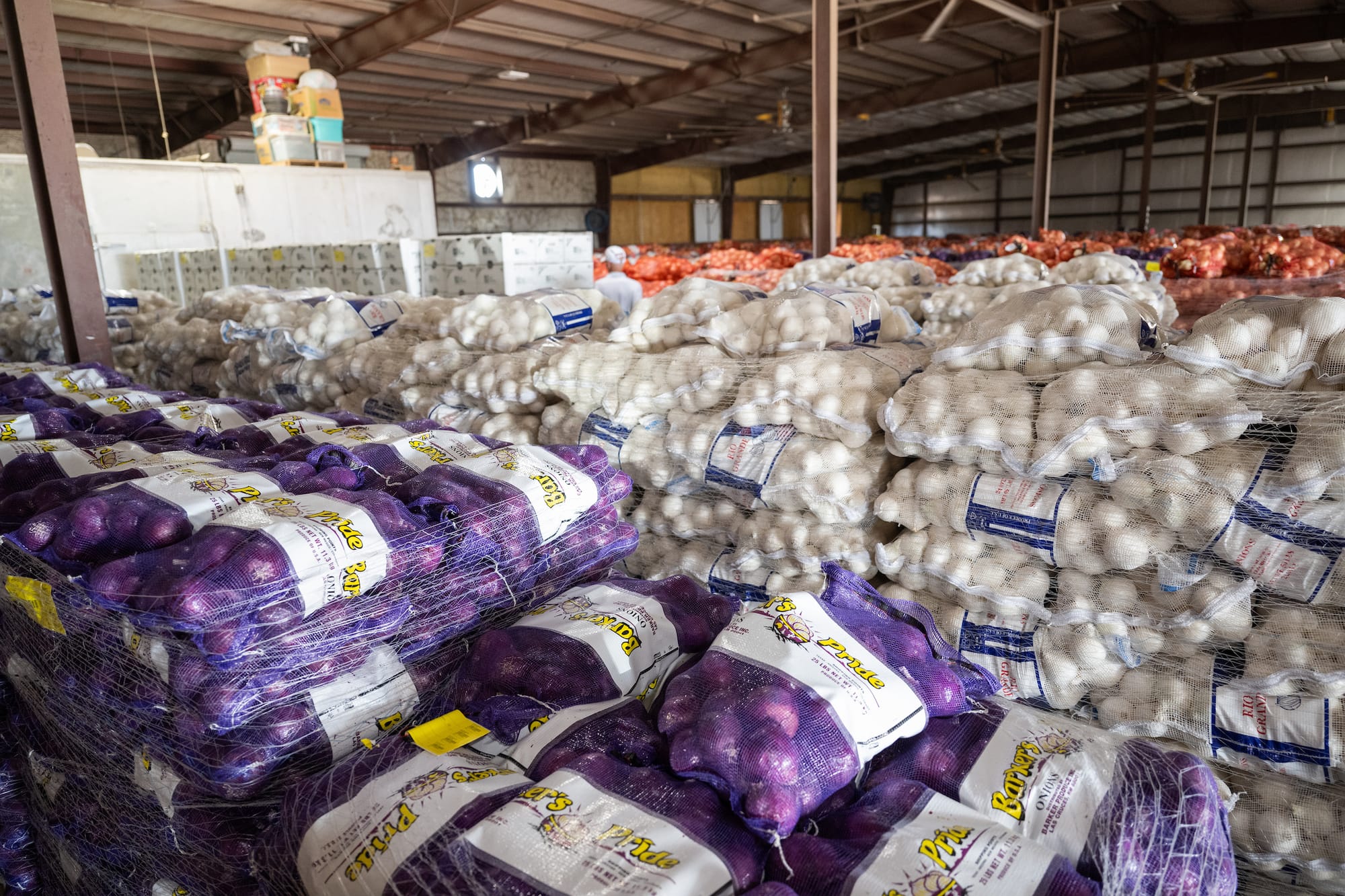 Stacks of bagged red and white onions fill a warehouse at Barker Produce.