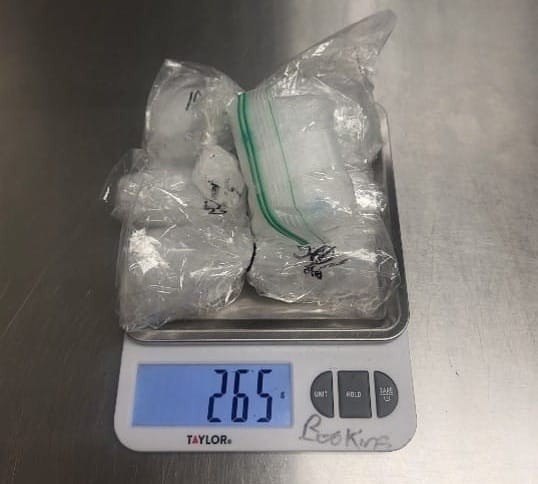 Several small plastic bags containing a white crystalline substance sit on a digital scale reading 265 grams.