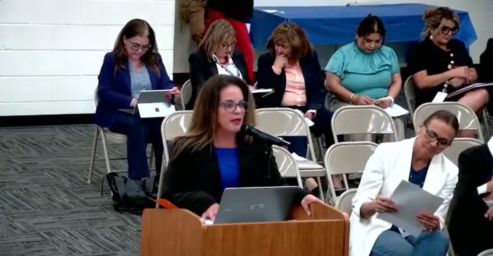 GISD Chief Academic Officer Maria Hernandez speaks at a podium during the Aug. 13 Board of Education meeting as district staff sit behind her.