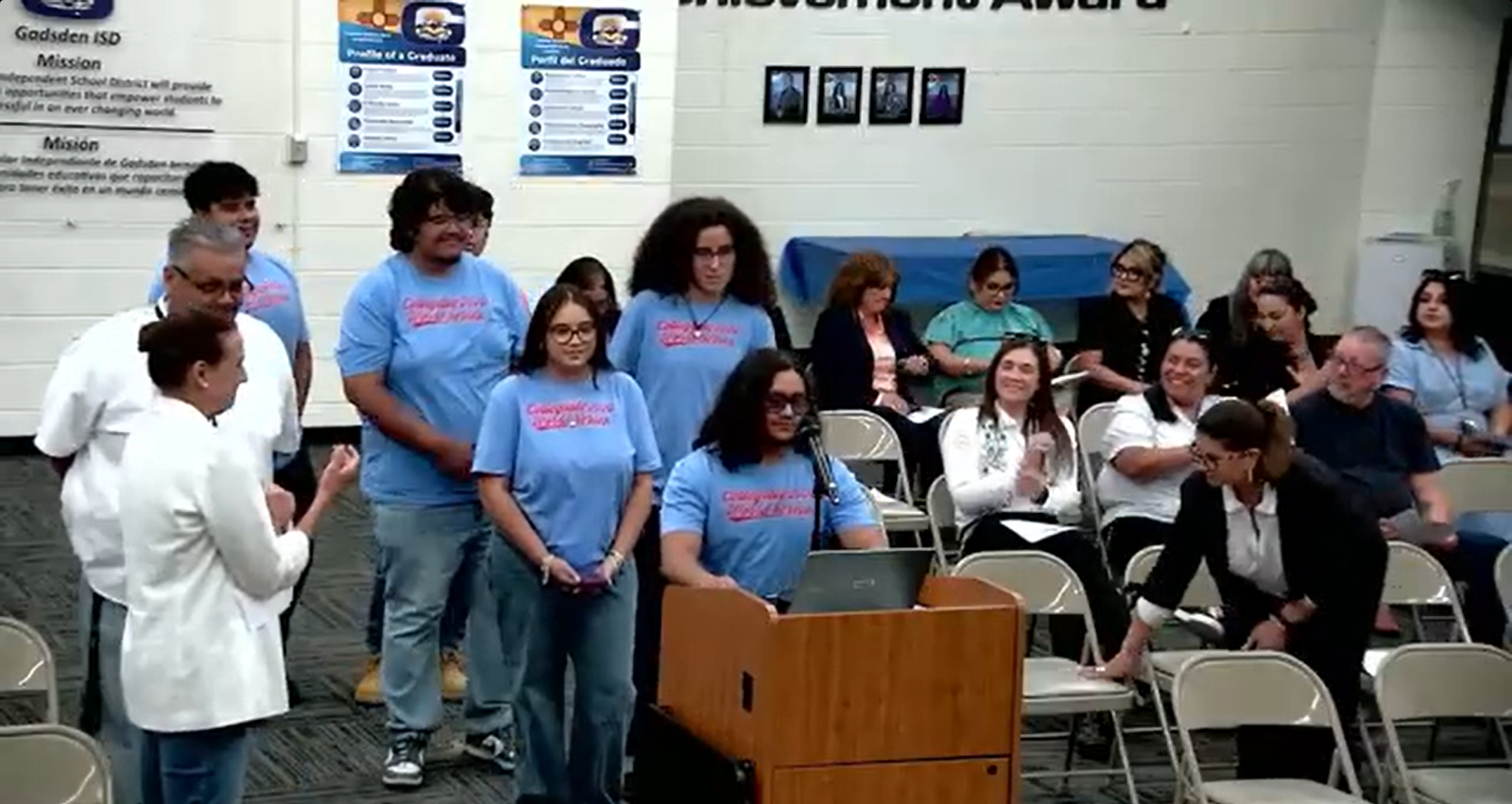 GISD students wearing matching blue shirts stand near the podium during an Aug. 13 Board of Education recognition for the National Hispanic Institute program.