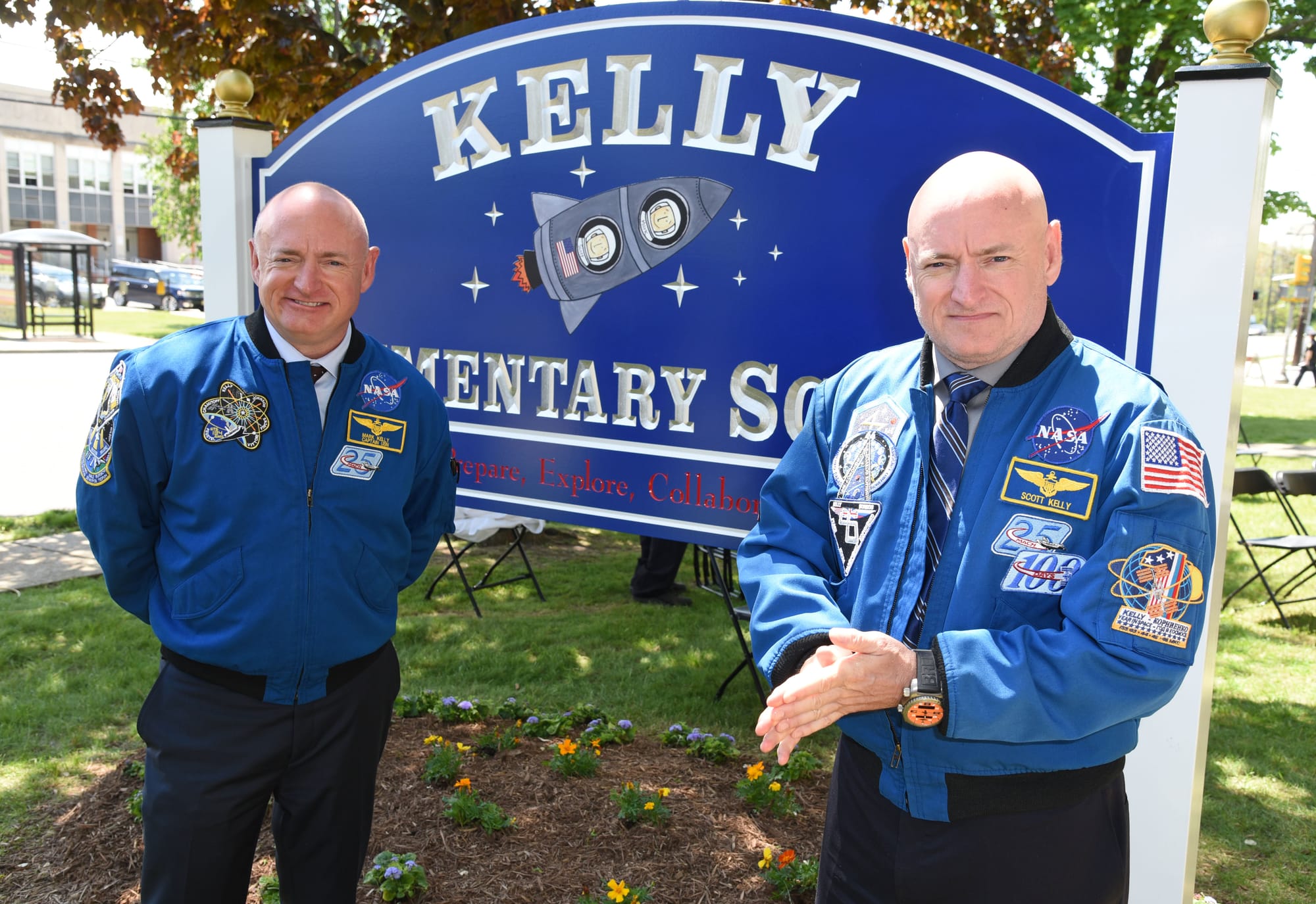 Mark Kelly, left, and Scott Kelly stand in NASA flight jackets outside Kelly Elementary School in New Jersey, which was renamed in their honor.