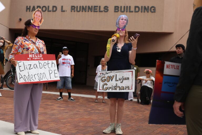 Protesters wearing masks depicting New Mexico officials stage a demonstration against Project Jupiter outside the New Mexico Environment Department in Santa Fe on Aug. 21.