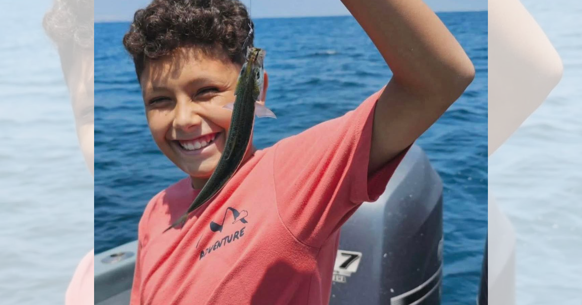 Chris Carnero smiles while holding up a fish during a boating trip.