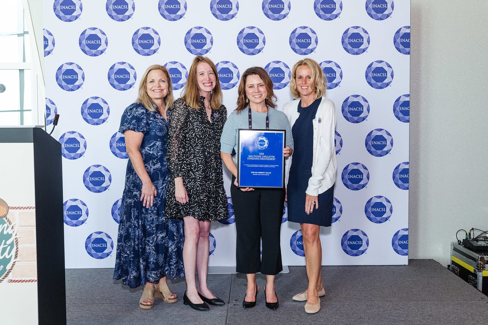 DACC Assistant Professor Andrea Cathey holds a framed Healthcare Simulation Standards Endorsement award with three women at an INACSL event.