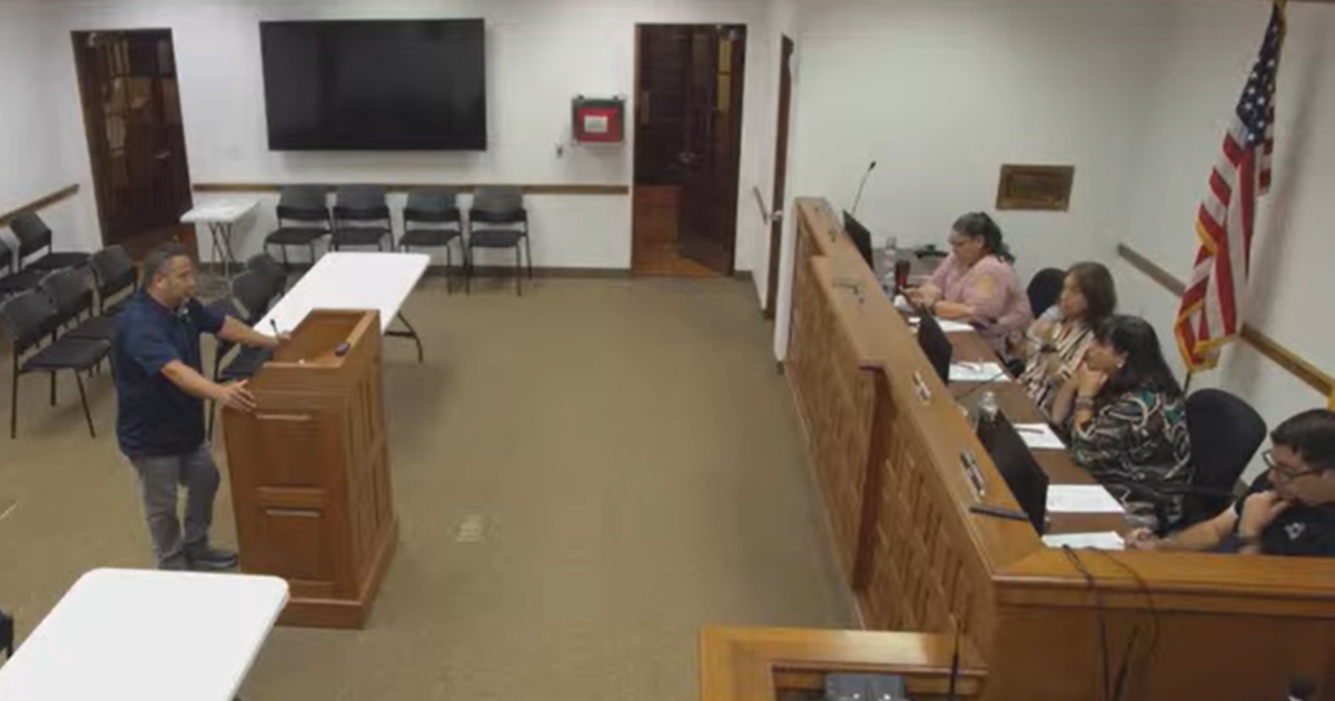 Eddie Salazar speaks at a podium before the Mesilla Board of Trustees on Oct. 20, 2026. Rows of public seating behind him are empty.