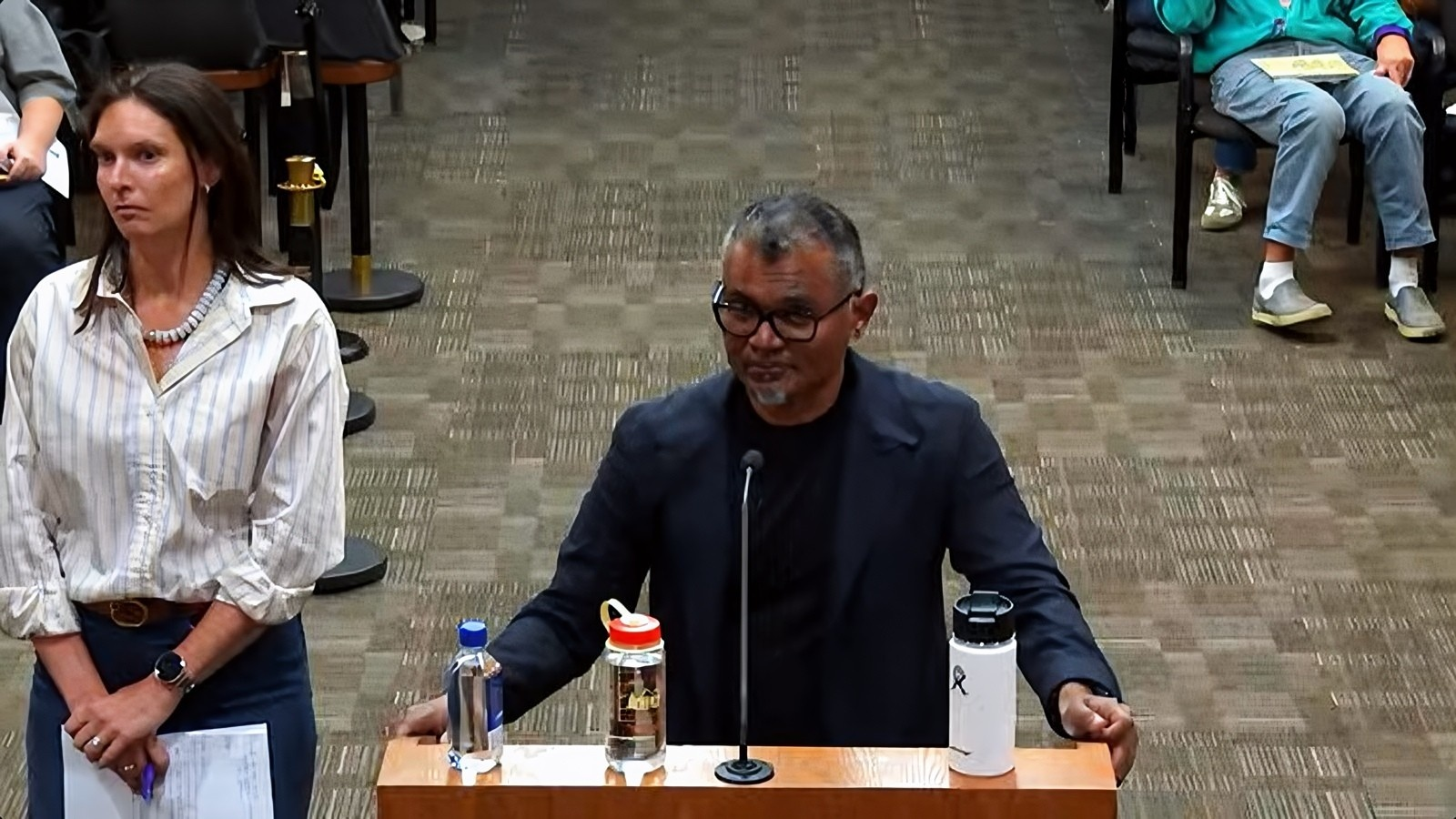 Oracle Executive Vice President Magesh Thiagarajan speaks at a podium during the Oct. 13 Doña Ana County Commission meeting as Julia Robin stands nearby.