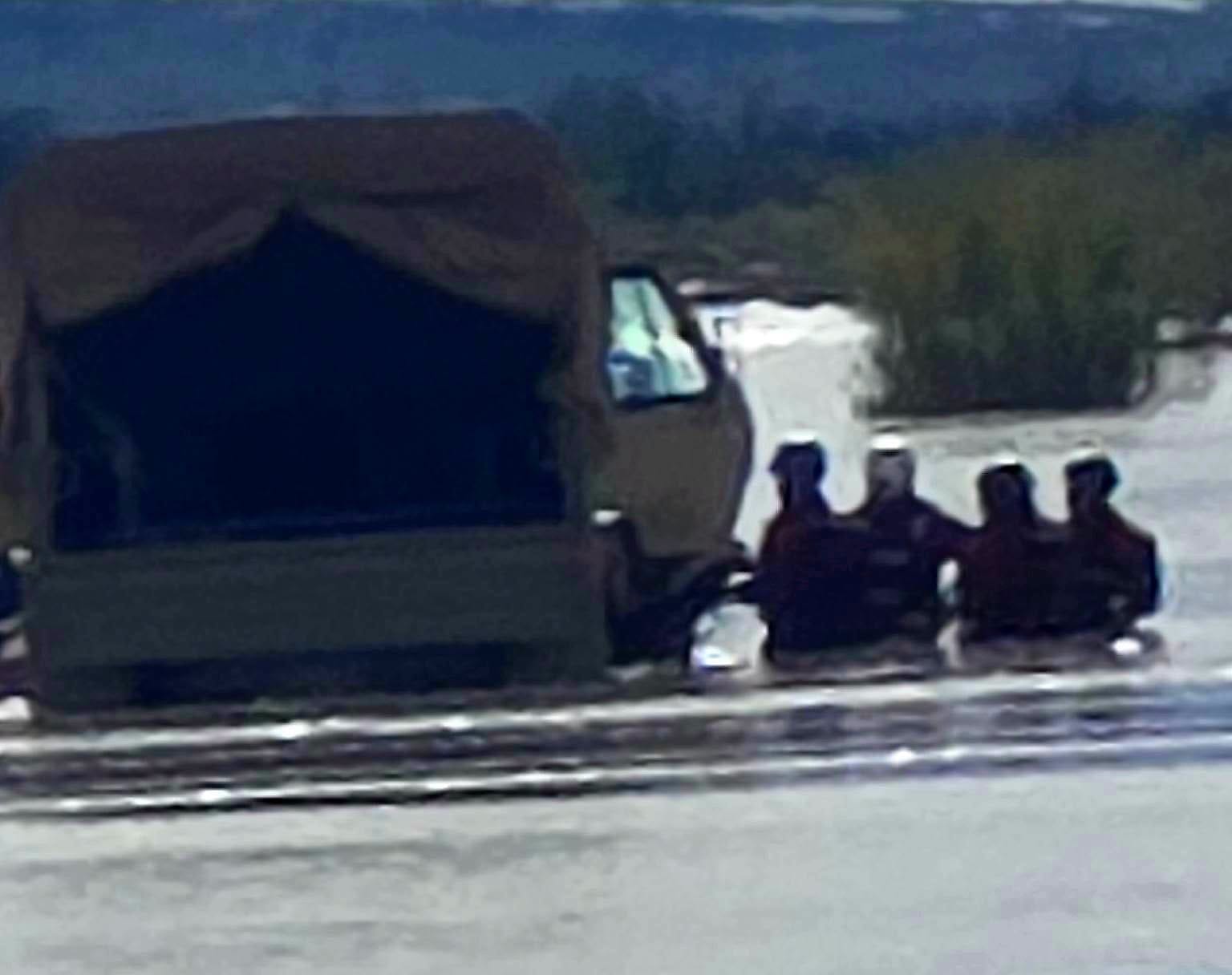 Four rescue personnel stand in deep, muddy floodwaters beside a military vehicle during a Rio Grande flood rescue operation in Socorro County.
