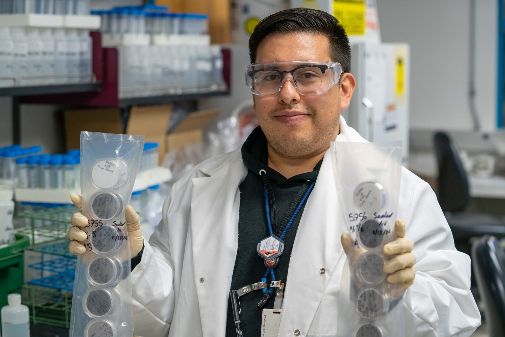 A researcher holds up two plastic packs full of Petri dishes that contain filters.