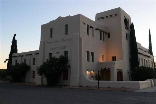 The former Doña Ana County courthouse in Las Cruces, a large white stucco building with a central tower and tall narrow windows, photographed at dusk.