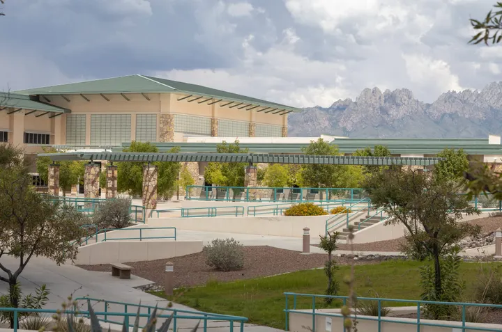 Doña Ana Community College East Mesa campus with landscaped walkways, stone pillars and the Organ Mountains in the background.