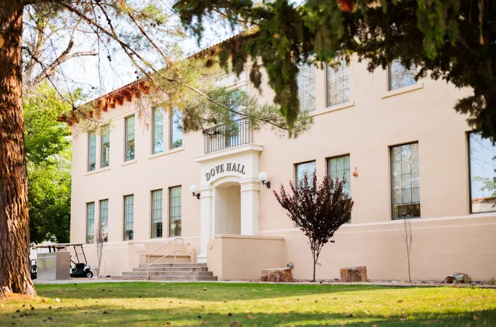Exterior of Dove Hall on the New Mexico State University campus, framed by trees and greenery.