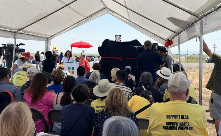Tina Cordova speaks at a RECA celebration near Trinity Site as attendees in yellow ‘Support RECA’ shirts listen.