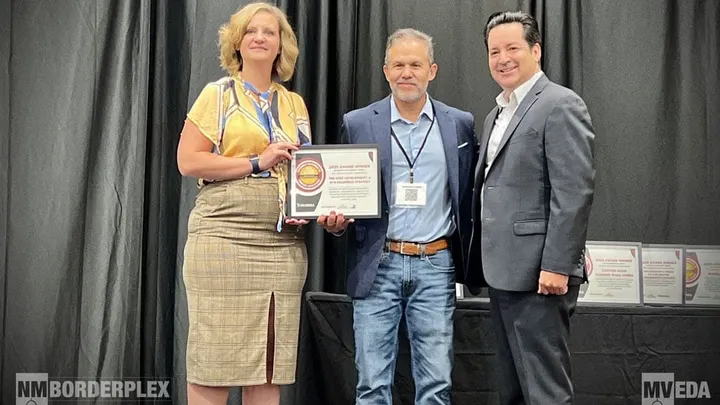 Three people stand on stage holding a framed award recognizing Las Cruces and MVEDA at the 2025 New Mexico Governor’s Economic Development Conference.