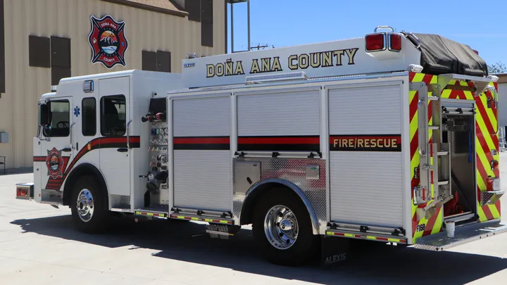 A Doña Ana County Fire Rescue truck parked outside a county fire station with the department’s emblem displayed on the building.