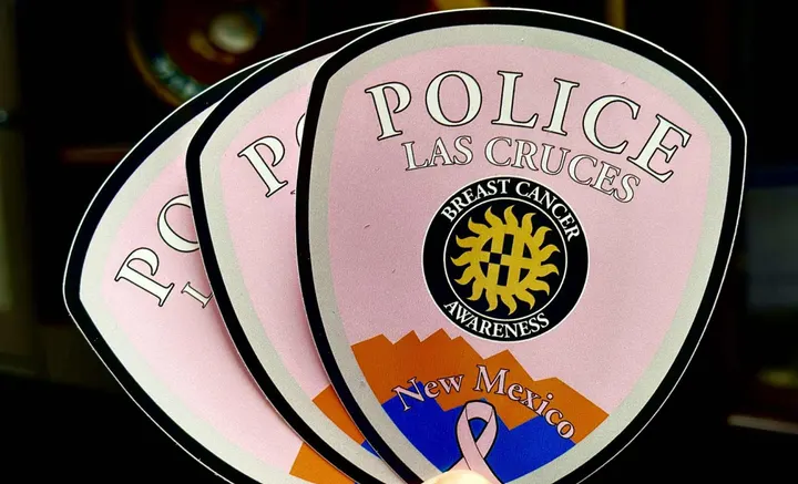 Three pink Las Cruces Police Department window decals promoting Breast Cancer Awareness, each showing the badge logo with a gold sun, mountains and a pink ribbon.